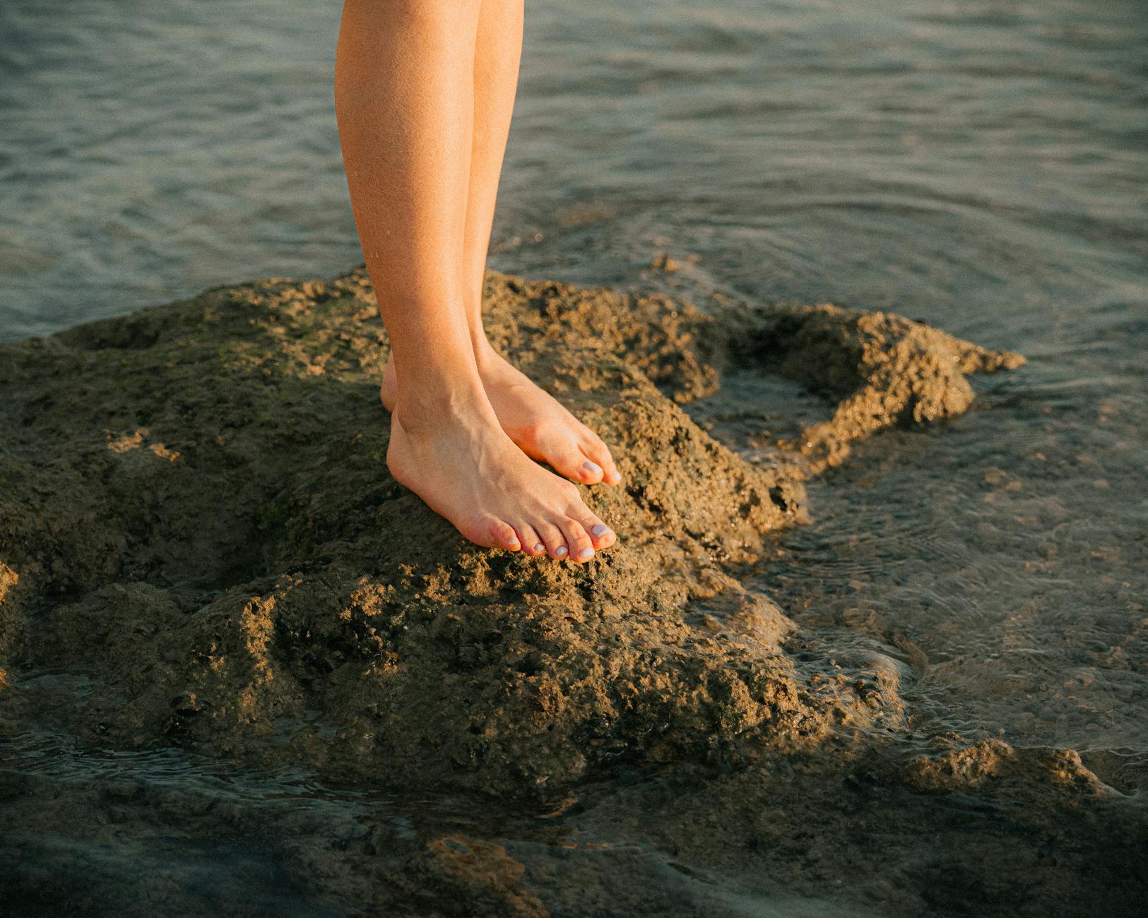 Captivating close-up of bare feet on rocky shore in Tel Aviv, Israel at sunset.