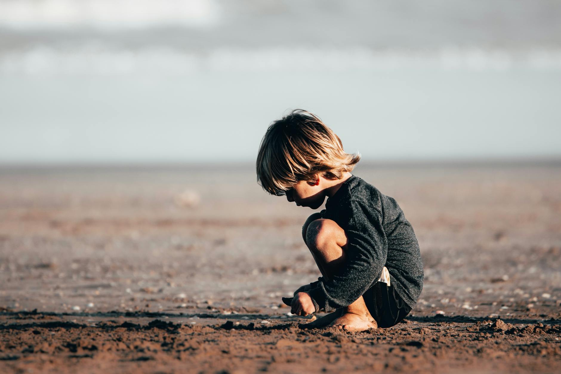 Young boy explores the sand on a sunny beach, capturing the essence of childhood play.