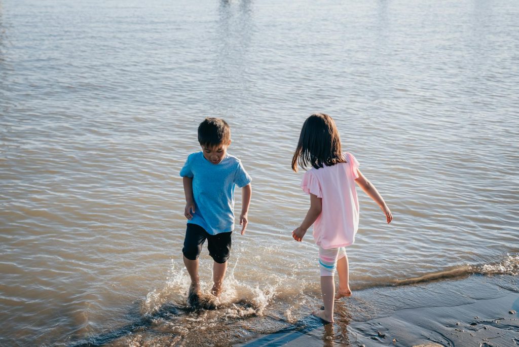 Home Two young children enjoying a playful day on the seashore, splashing in the water.