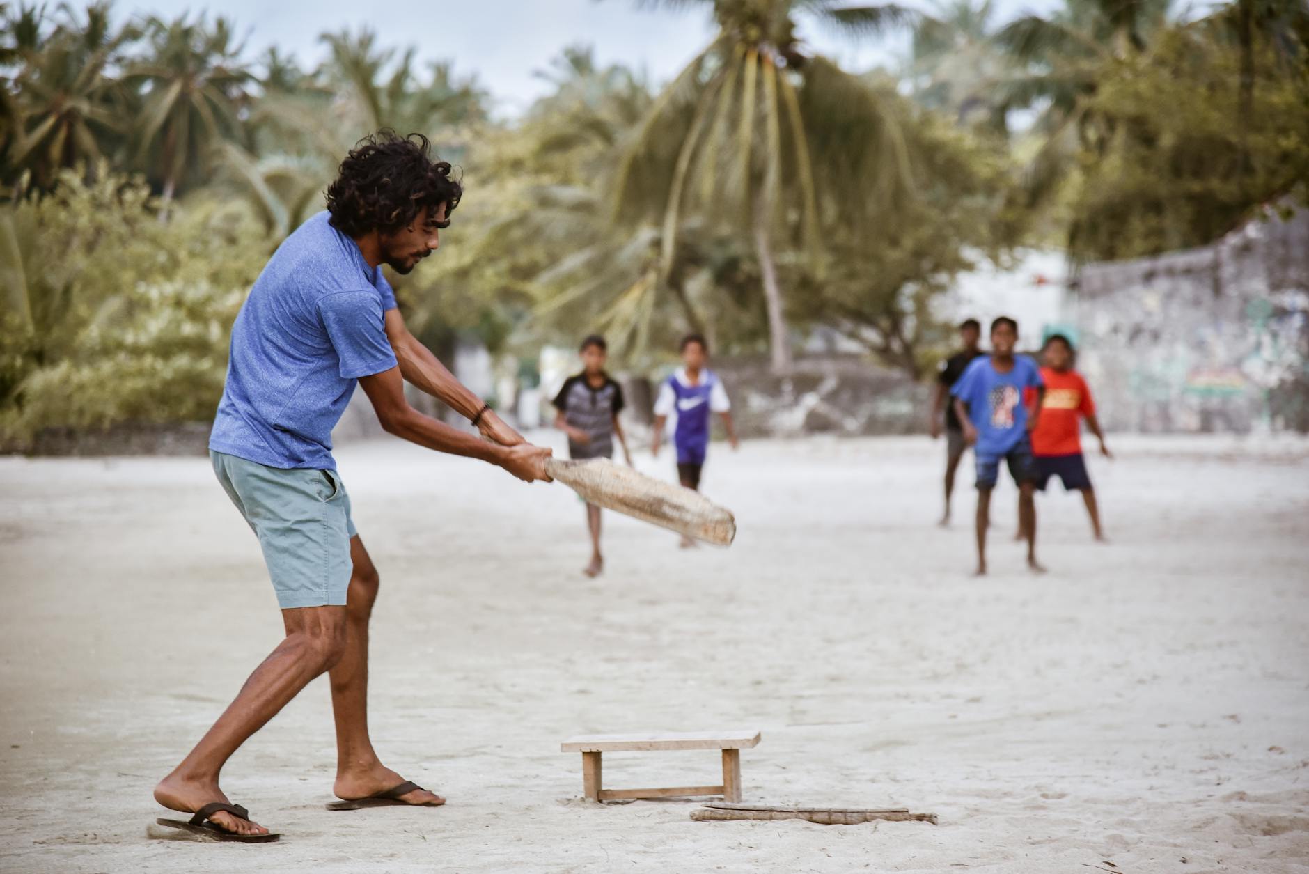 A lively beach cricket match with kids and adults on a sandy Maldives beach.