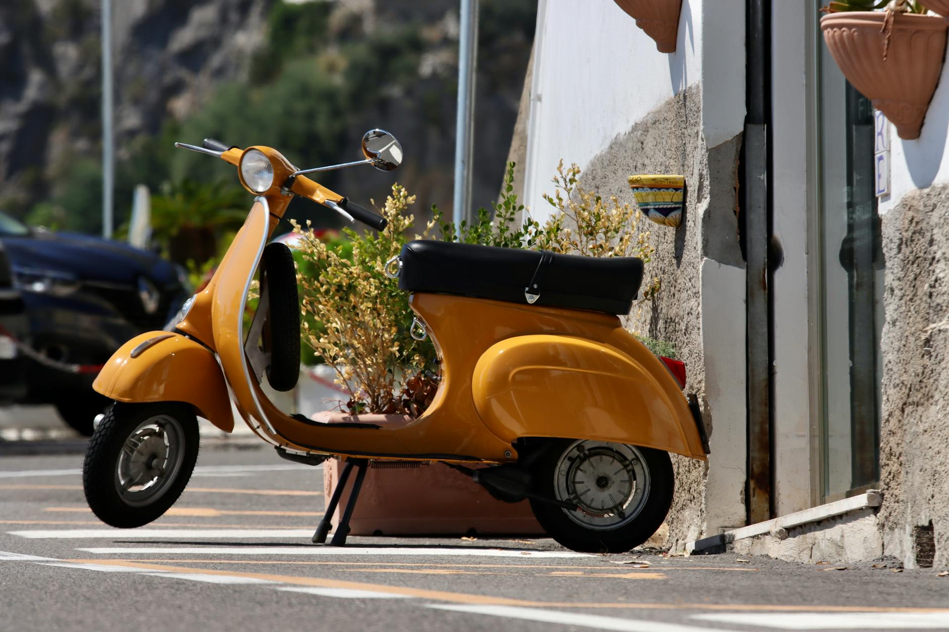 Charming yellow vintage scooter parked in a sunny Italian street setting.