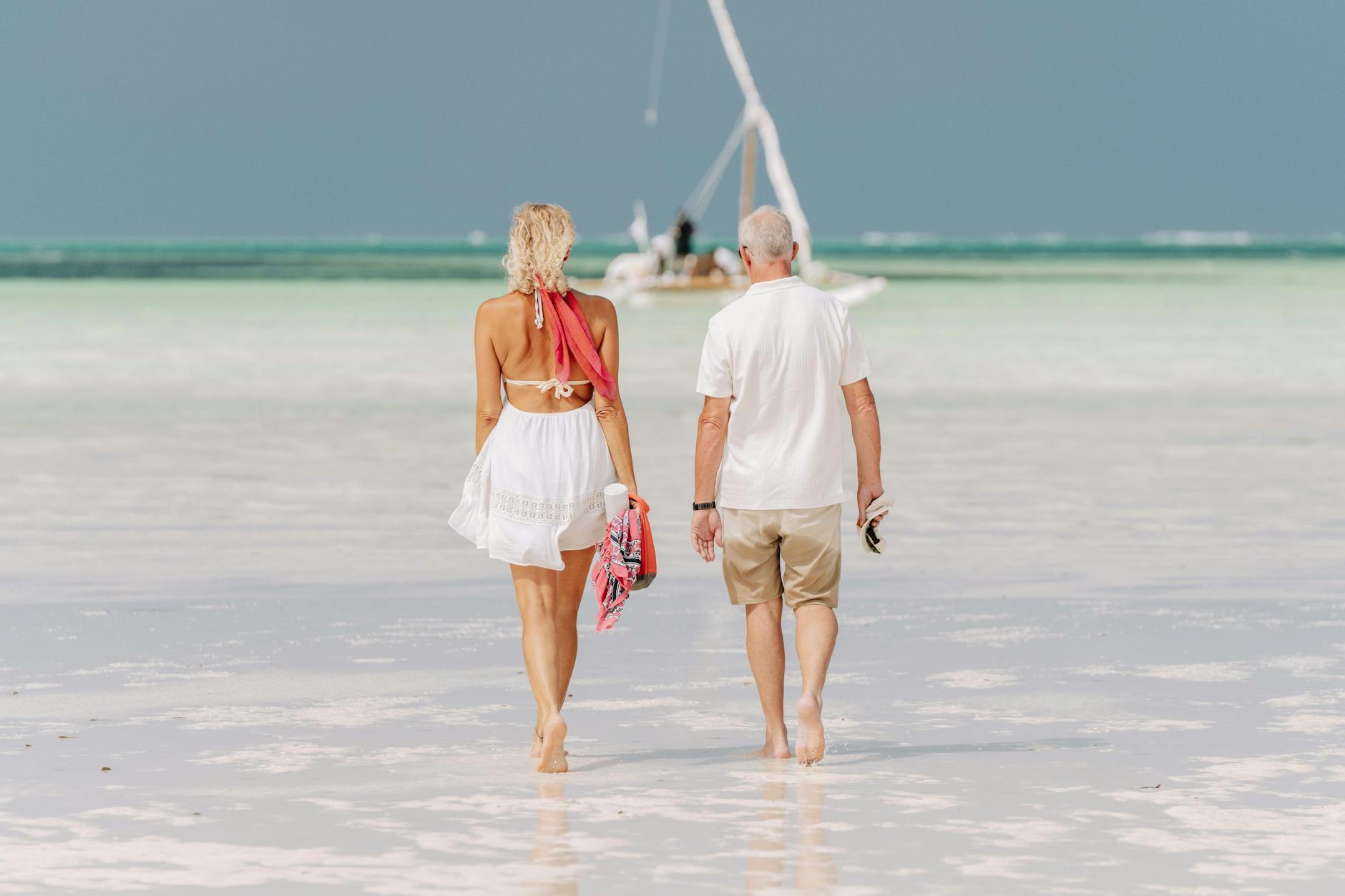 Elderly couple walks barefoot along a serene Zanzibar beach. Perfect travel and relaxation concept.
