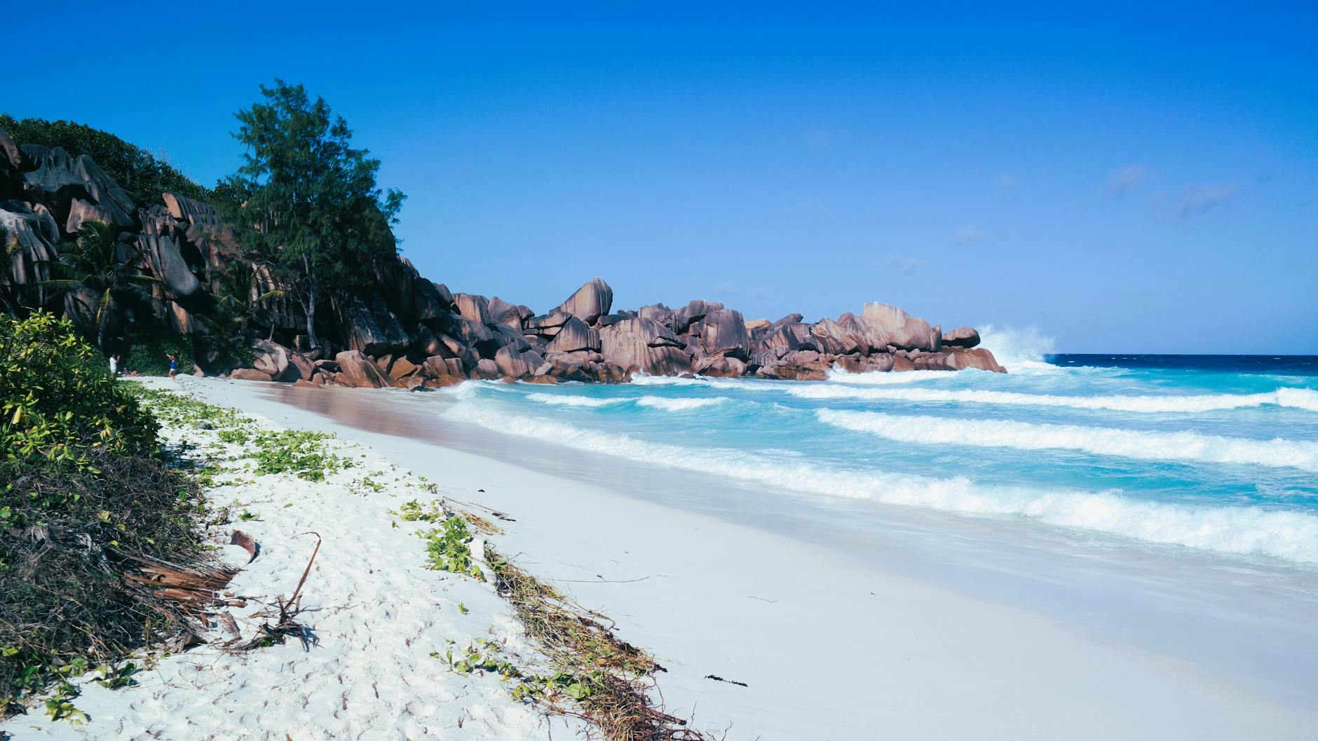 Pristine tropical beach with azure waves crashing against rocky coastline.