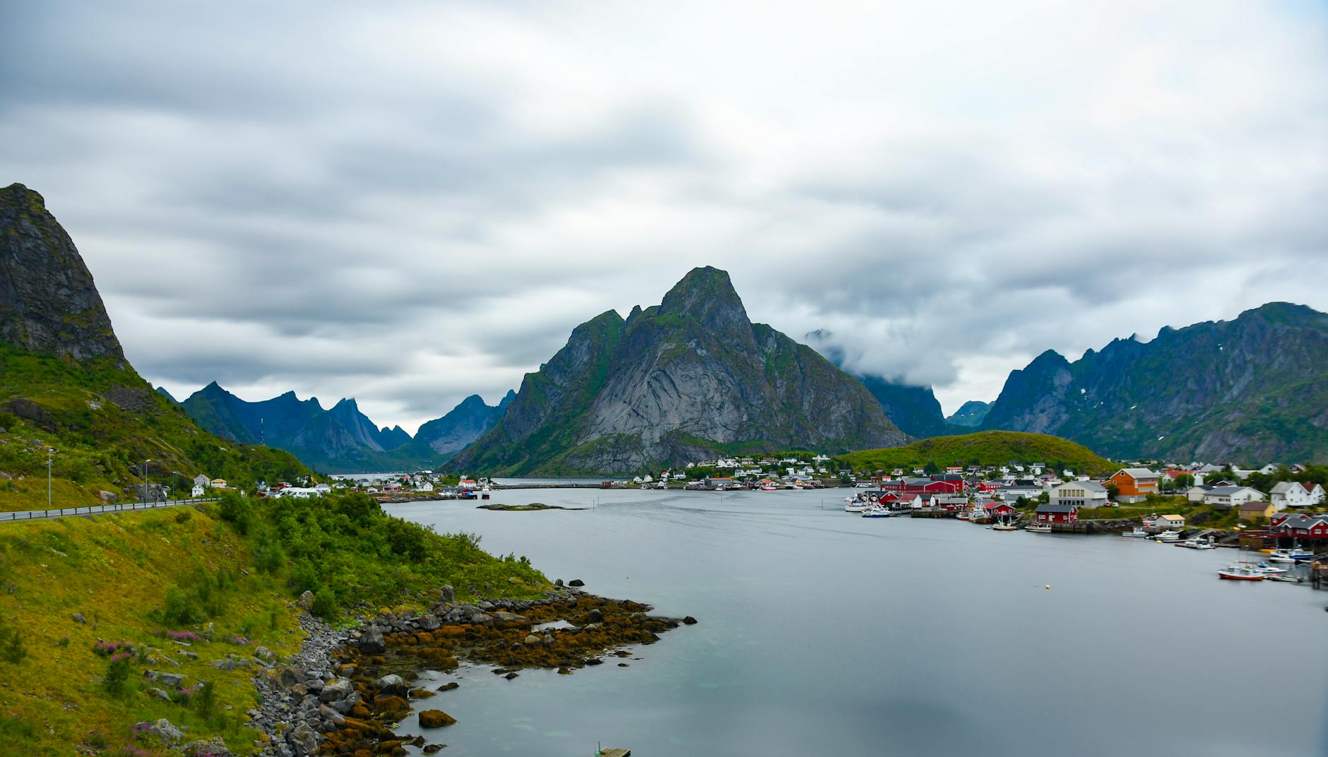 Beautiful view of a small village nestled by a mountain and lake in Norway under cloudy skies.